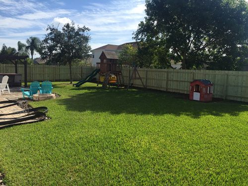 Wood fence surrounding backyard and kid's playground